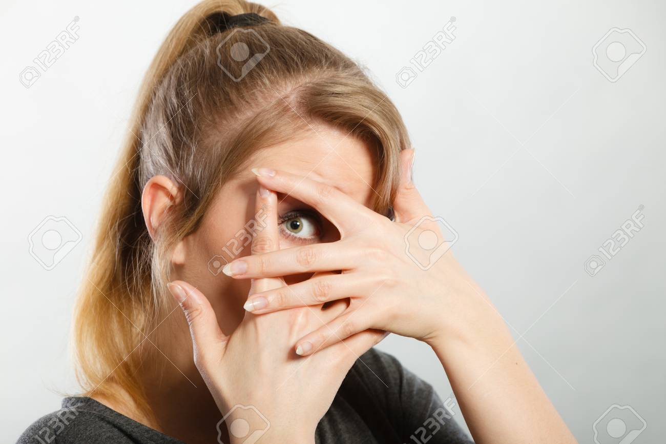 注意恥観察心理障害概念 内気な少女は 彼女の顔を隠します 頭の残りの部分をカバーしながら彼女の指を見て若い金髪好奇心旺盛な女性 の写真素材 画像素材 Image