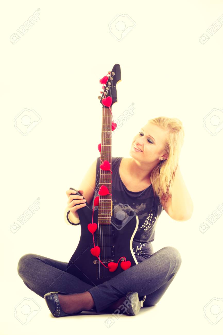 音楽が大好きです 黒いエレキギターで若いきれいな女の子 演奏への情熱を持つ金髪の女性 女性ミュージシャンは楽器を保持します の写真素材 画像素材 Image