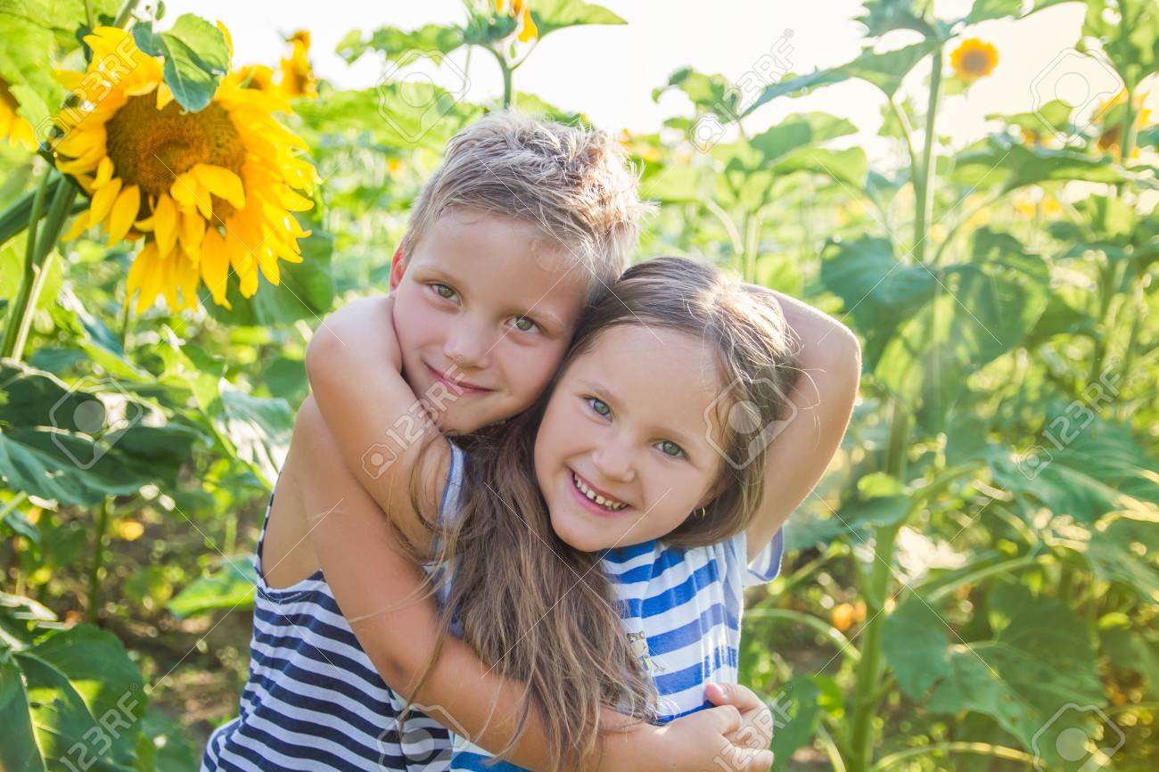 happy boy and girl hugging among sunflower field stock photo