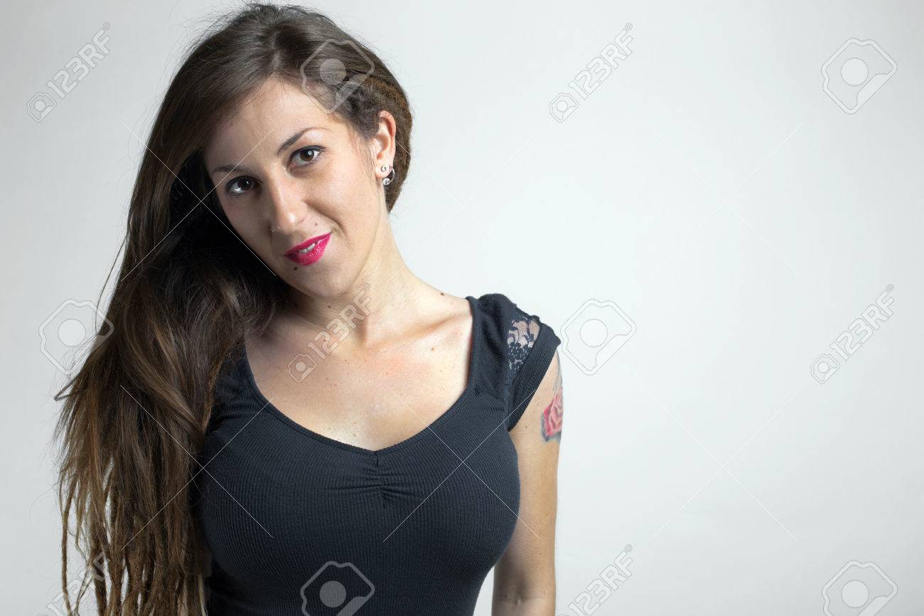 若い女性の腕のタトゥーと白い壁のスタジオでポーズをとって長い髪と若いセクシーな女性の肖像画スタジオでポーズ タトゥー 彼女の腕でローズの の写真素材 画像素材 Image