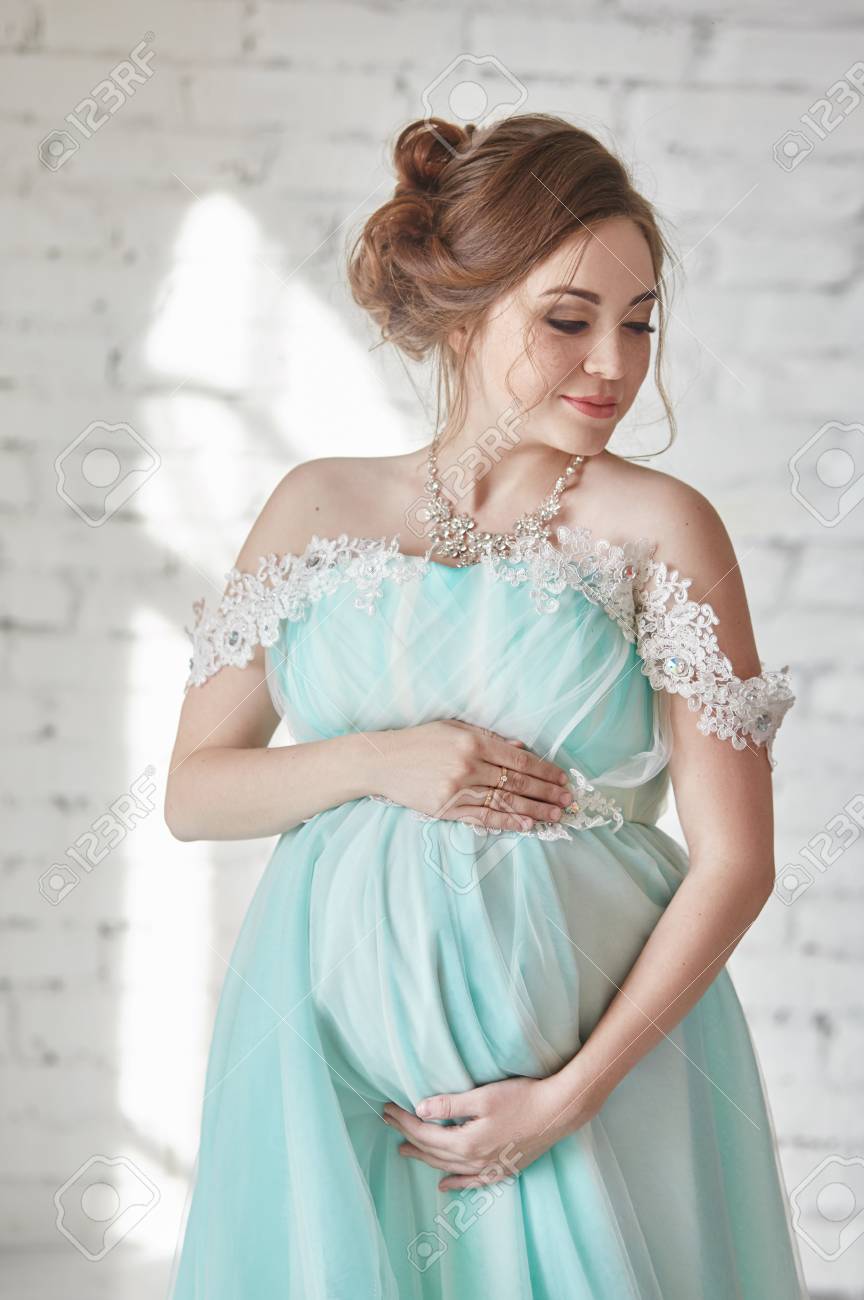 Happy Pregnant Woman In Long Evening Dress Touching Belly Hands