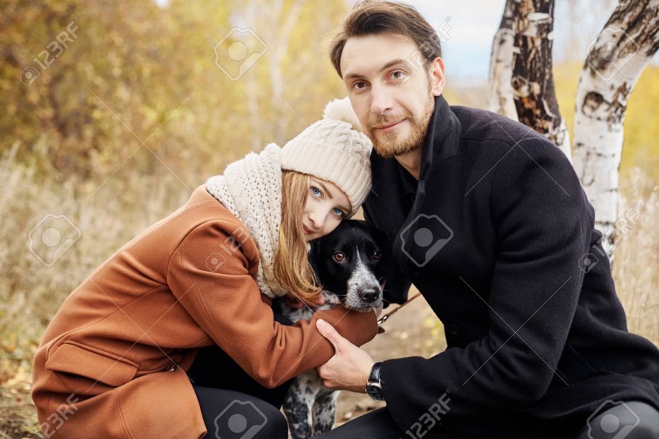 公園で犬を連れて歩いて ハグのカップル 秋の散歩男性と女性の犬 秋の風景に愛とロマンス の写真素材 画像素材 Image