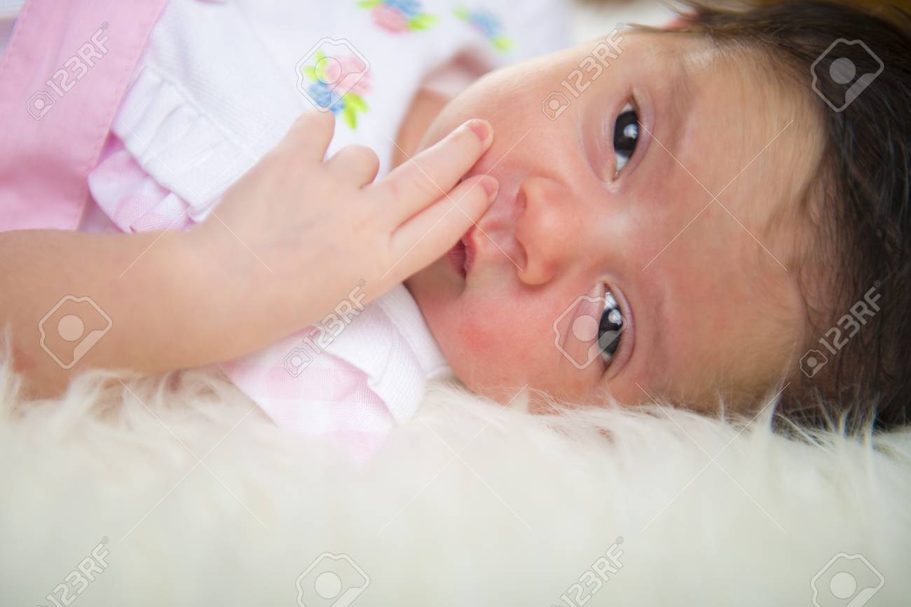 生まれたばかりの女の子が幸せで 白い毛の毛布でリラックスした ピンクの服を着て横になっています の写真素材 画像素材 Image