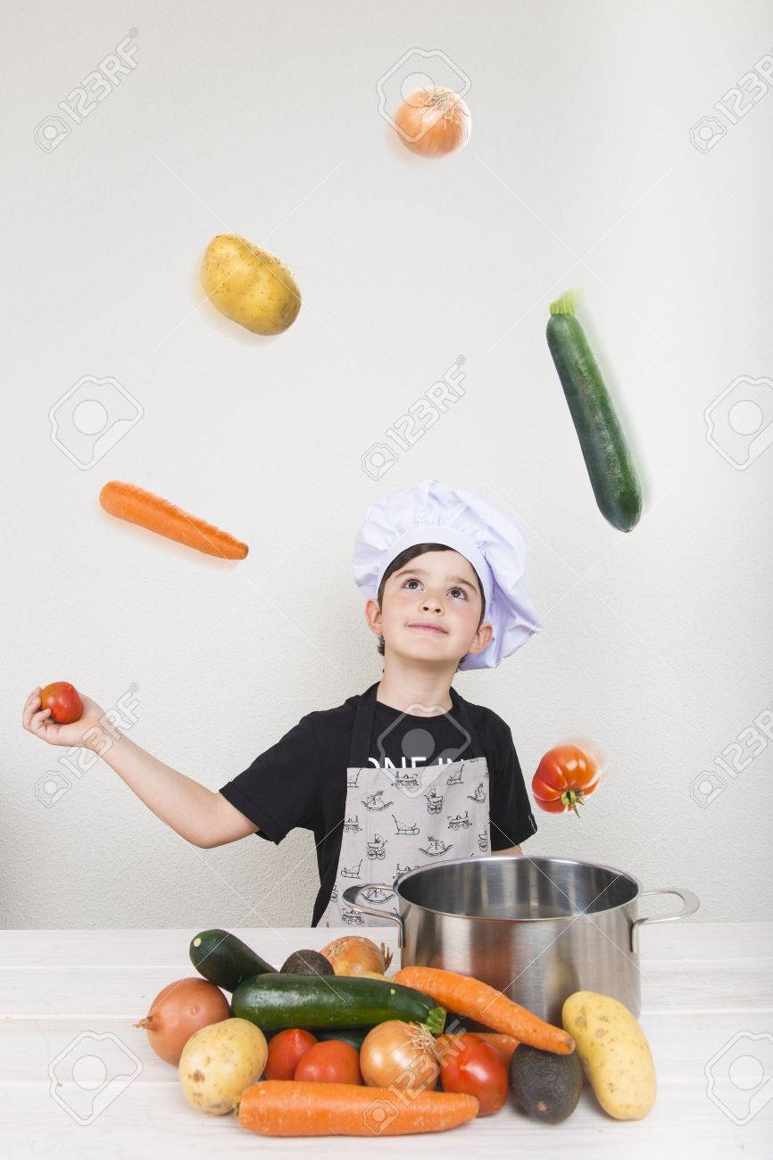 Child cooking with vegetables making them fly - 59117424 Child cooking with vegetables making them fly - 59117424