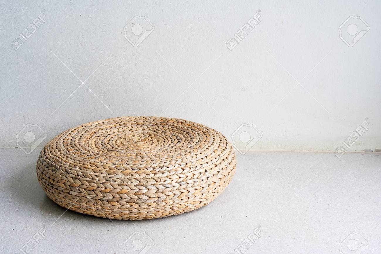 Chaise ronde en osier brun dans un décor de style vintage sur un sol en béton dans une salle blanche éclairée par la lumière naturelle. Chaise ronde en osier brun dans un décor de style vintage sur un sol en béton dans une salle blanche éclairée par la lumière naturelle.