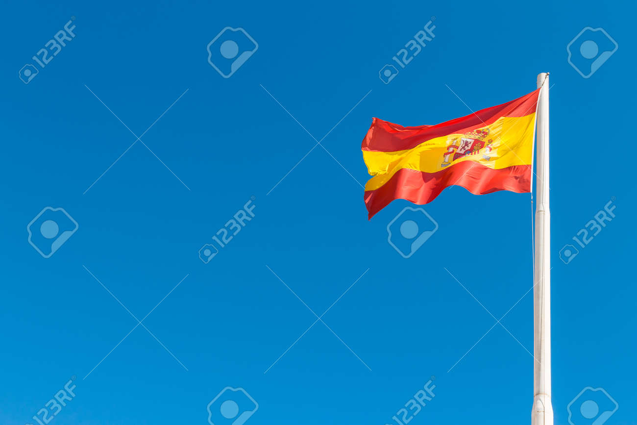 スペインの国旗は青い空で手を振っています スペインの旗 の写真素材 画像素材 Image