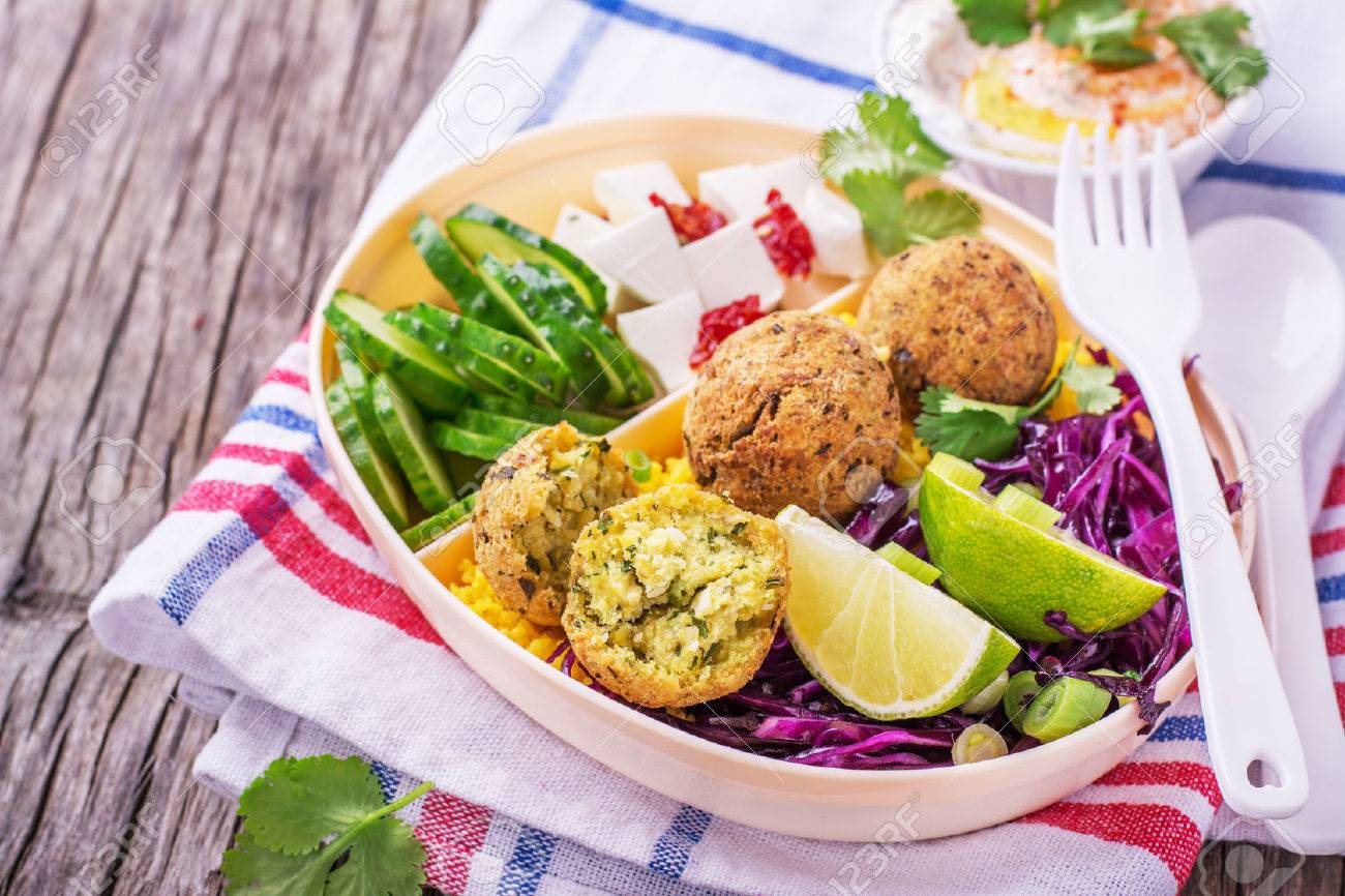 Box Lunch on the road for a picnic or to the office for lunch with cous cous, falafel chick peas, red cabbage salad, slices of cucumber, feta cheese and salad hummus in a white plastic container with a fork and spoon decorated with sprigs of cilantro. sel - 51977481 Box Lunch on the road for a picnic or to the office for lunch with cous cous, falafel chick peas, red cabbage salad, slices of cucumber, feta cheese and salad hummus in a white plastic container with a fork and spoon decorated with sprigs of cilantro. sel - 51977481