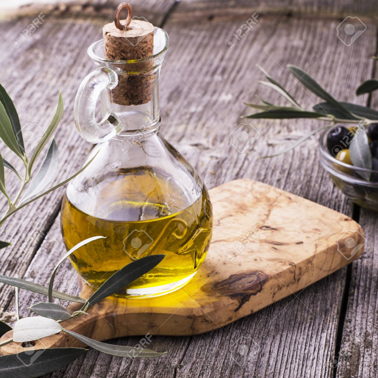 Jug With Extra Virgin Olive Oil On Olive Cutting Board Surrounded By Branches Of The Olive Tree And Olives Selective Focus The Concept Of A Healthy Natural Food Stock Photo Picture And