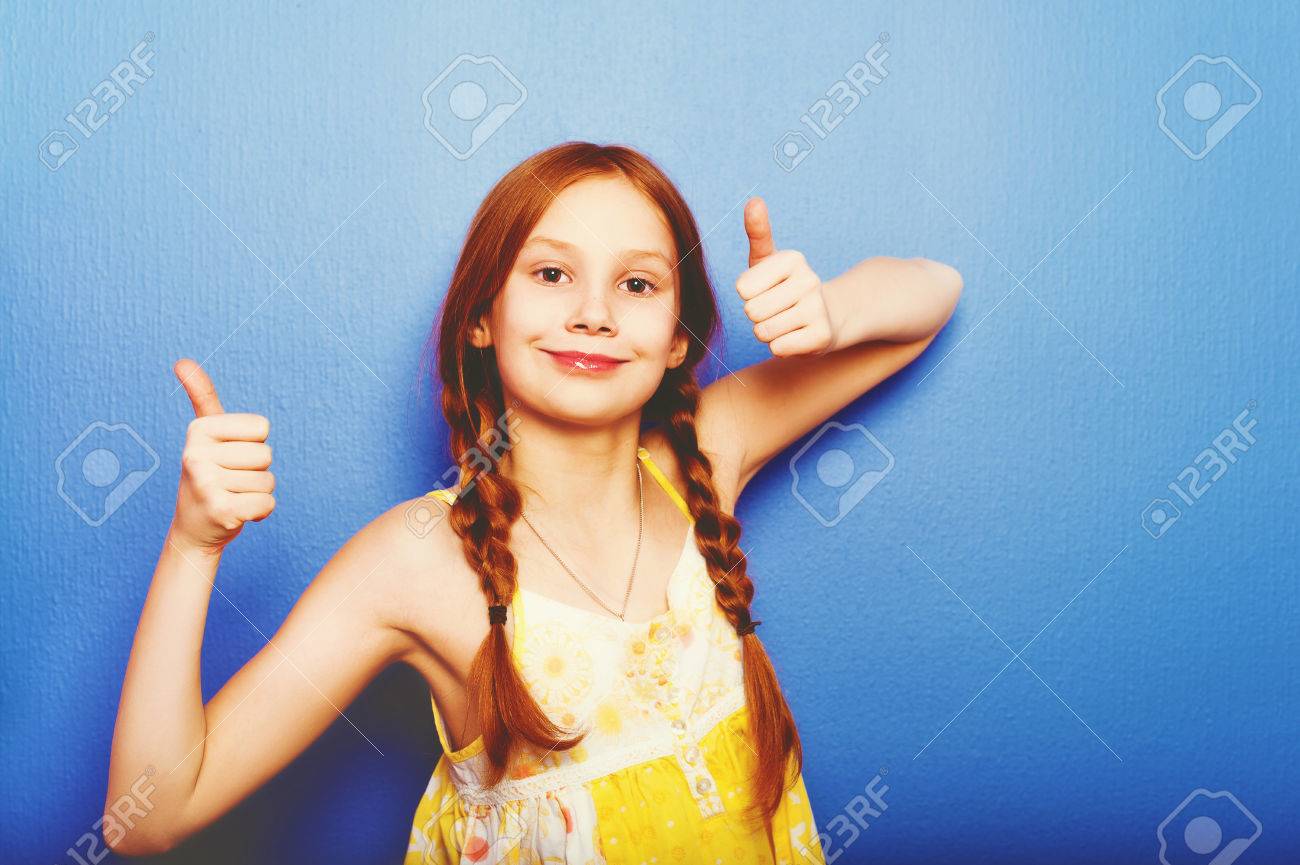 Prise De Studio Dune Jeune Fille Nue De 9 À 10 Ans Avec Une Jeune Fille En  Peluche Portant Un Top Jaune, Debout Contre Un Fond Violet Bleu, Un Grand  Pouce Vers