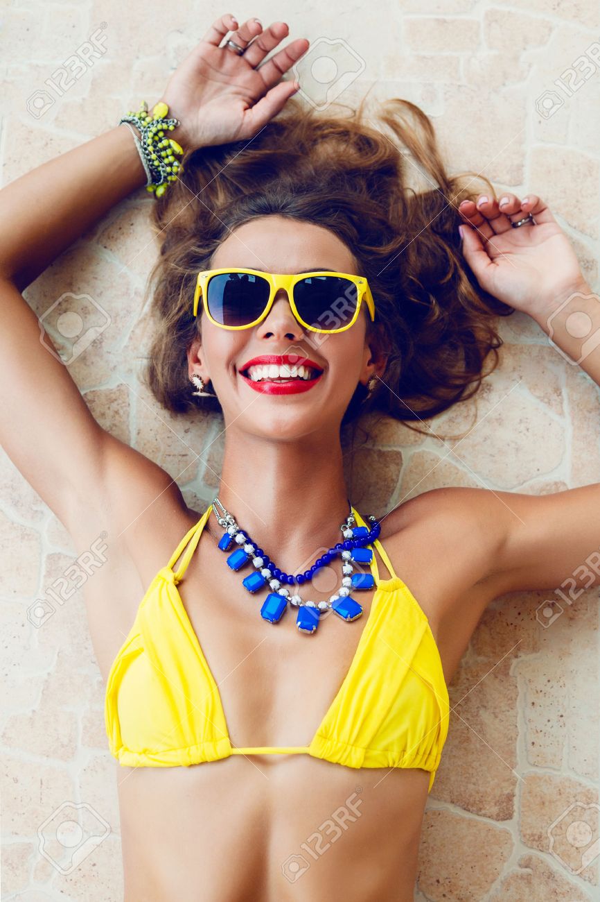 Happy pretty brunette woman smiling and having fun in hot summer day, wearing stylish neon bikini sunglasses and jewelry - 30190561 Happy pretty brunette woman smiling and having fun in hot summer day, wearing stylish neon bikini sunglasses and jewelry - 30190561