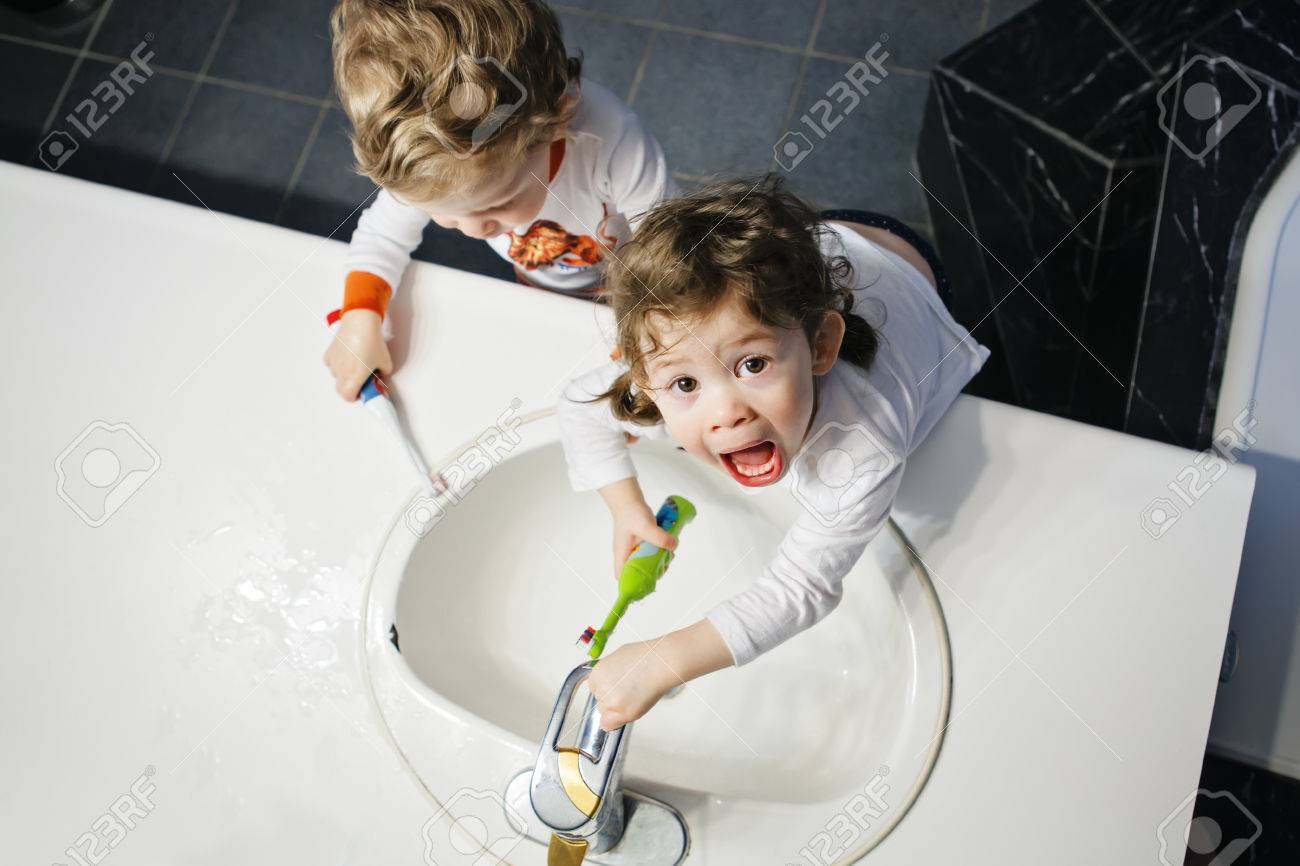 Closeup portrait of twins kids toddler boy girl in bathroom toilet washing face hands brushing teeth with toothbrash playing with water, lifestyle home style, everyday moments, top view - 64550175 Closeup portrait of twins kids toddler boy girl in bathroom toilet washing face hands brushing teeth with toothbrash playing with water, lifestyle home style, everyday moments, top view - 64550175