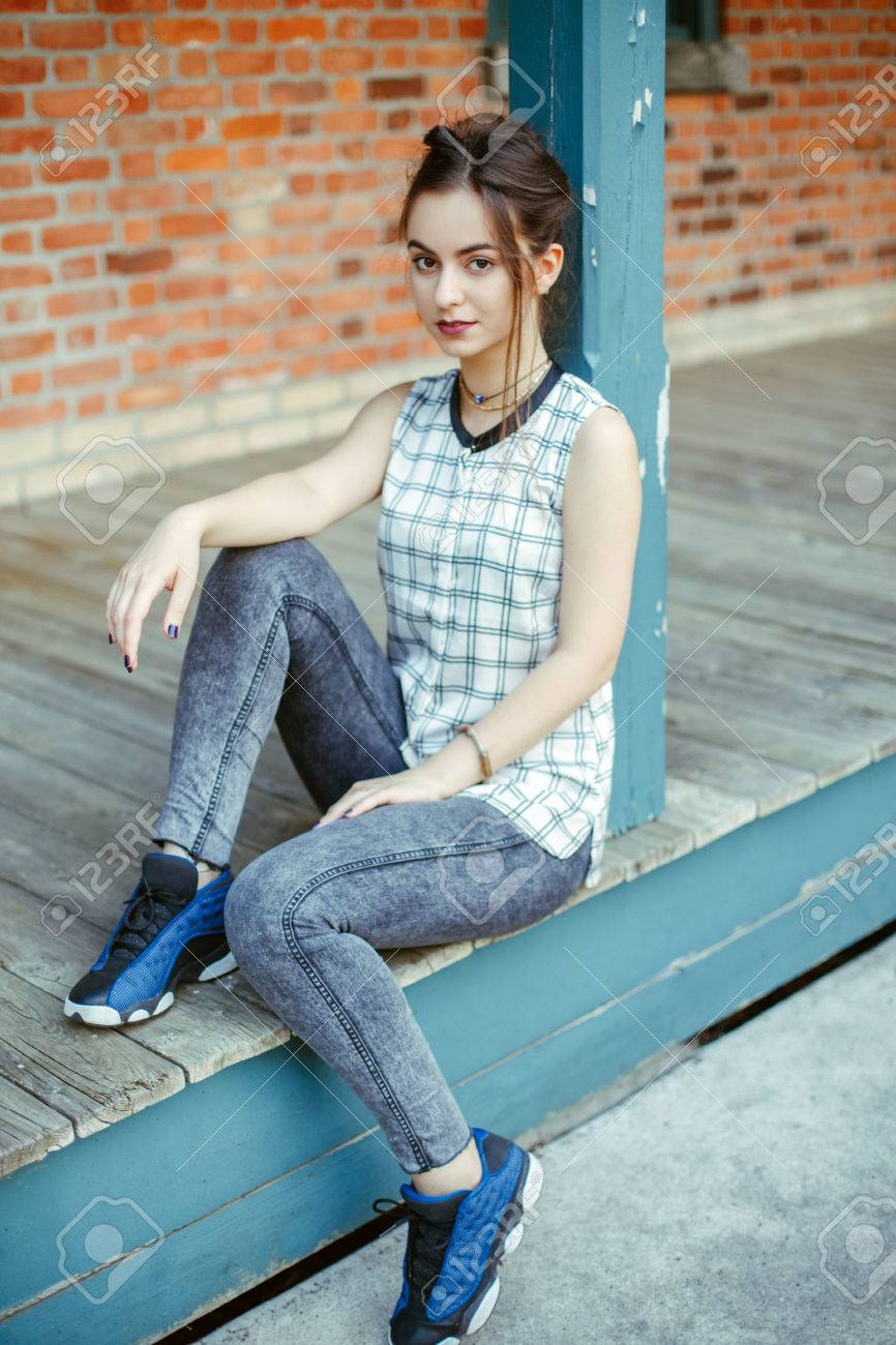 街撮り 主婦ポートレート 物思いにふける若い中東白人ユダヤ人美人カメラで探して黒髪お団子、黒茶色の目でのポートレート、クローズ アップ。レンガの壁に白の格子縞のシャツの女の子。自然の美しさの写真素材・画像素材 Image 82233594