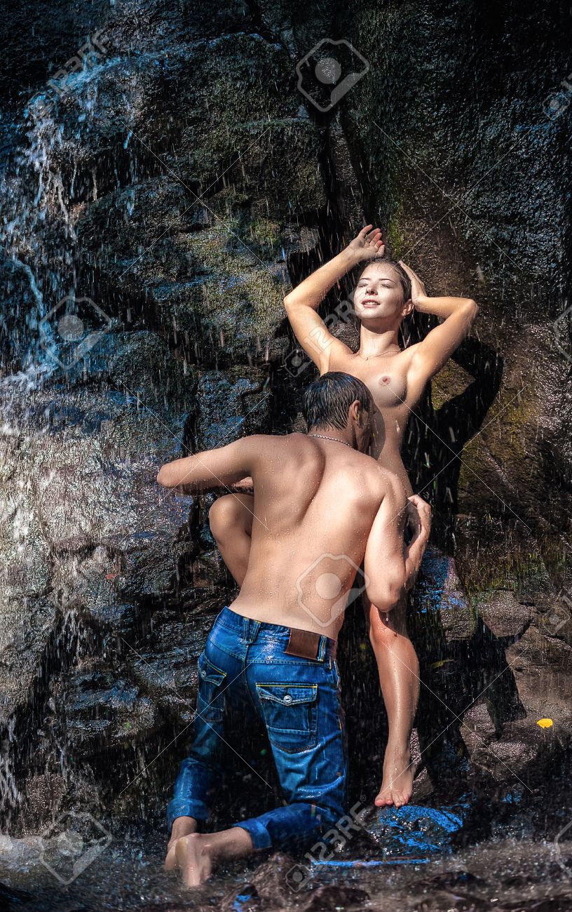 couple hugging and kissing under waterfall stock photo picture and
