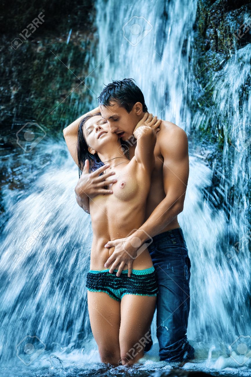 couple hugging and kissing under waterfall stock photo picture and
