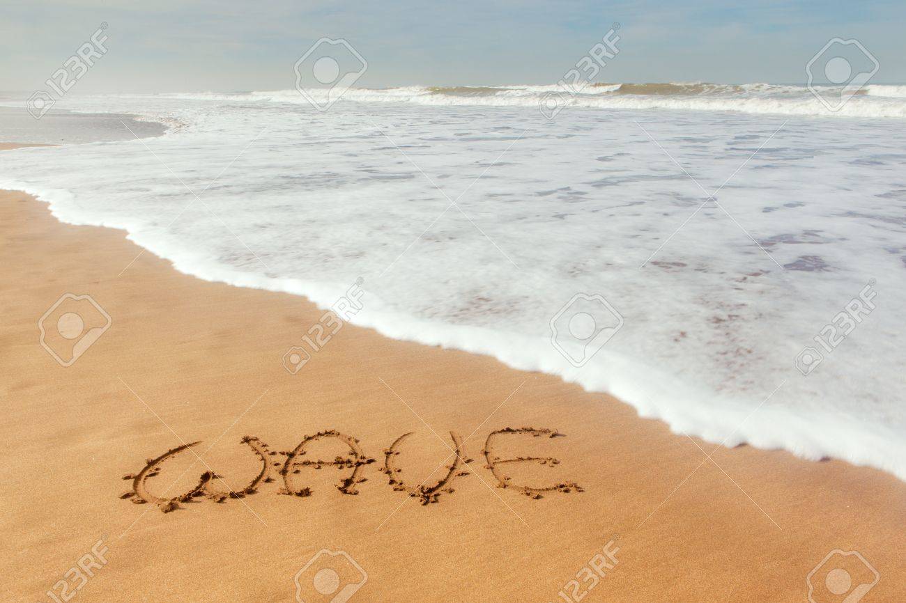 single word wave written on sand with ocean waves flowing stock