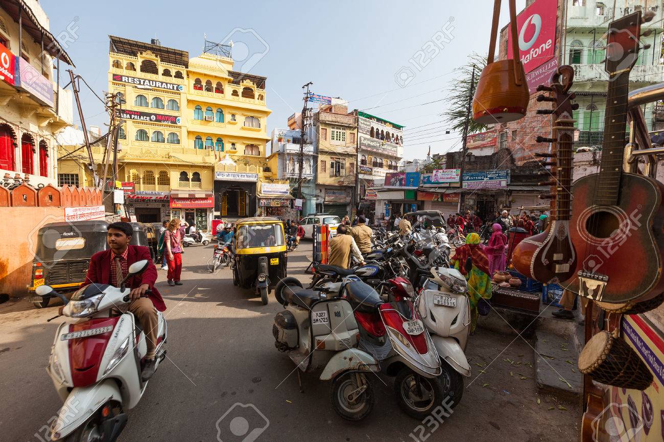 busy restaurant scene. stock photo - udaipur, india january 16, 2015 : busy street scene in jagdish chowk, a central town square udaipur filled with mopeds, rickshaws, restaurant r