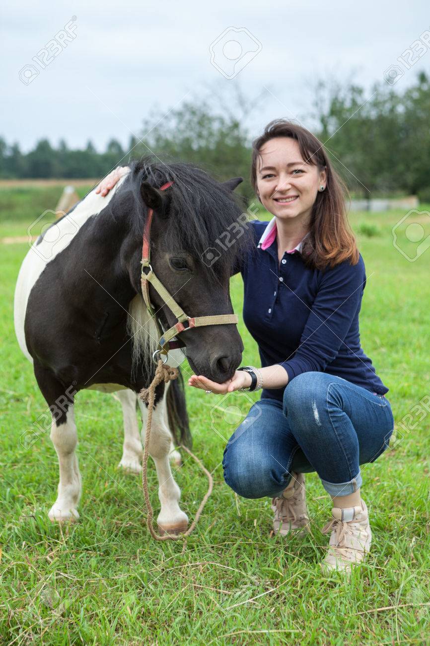 Hermosa Mujer Sentada Con Un Pequeño Poni Y Caballo De Alimentación. Campo  Fotos, retratos, imágenes y fotografía de archivo libres de derecho. Image  61632153