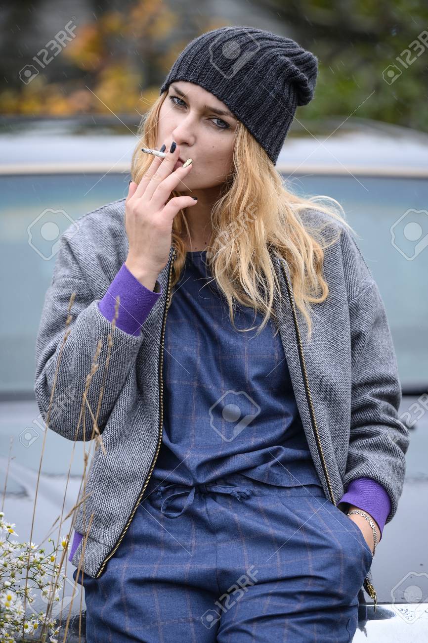 よく服を着てかなり若い白人金髪アダルト 10 代でかわいい女の子田舎風景の春や秋の天気落ち込んで気分でタバコを吸って車近くのファッションのドレス の写真素材 画像素材 Image