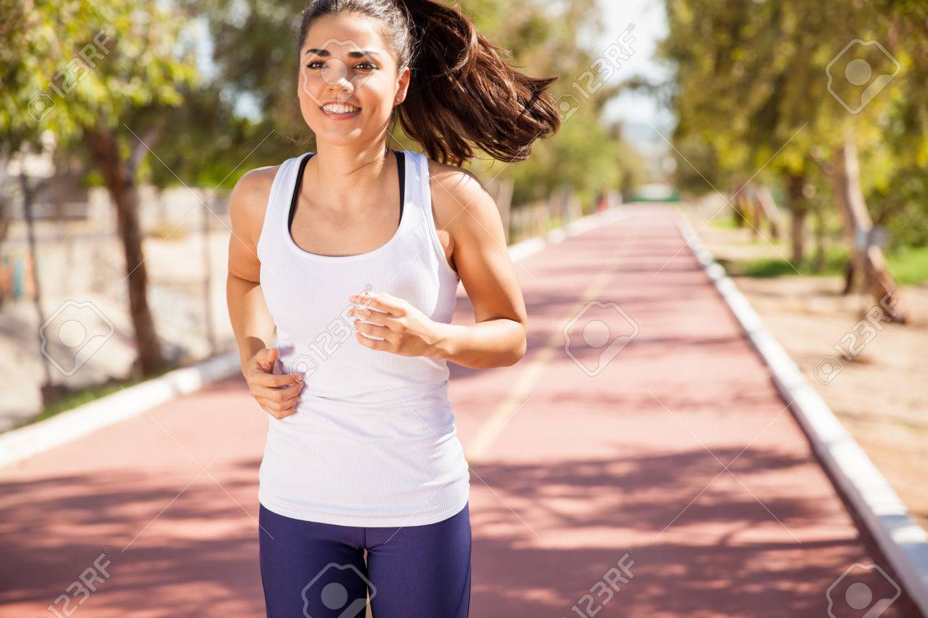 Девушка в белой футболке бежит. Счастливый бегун. Девушка на пробежке. Женщина бежит. Девушка бежит.