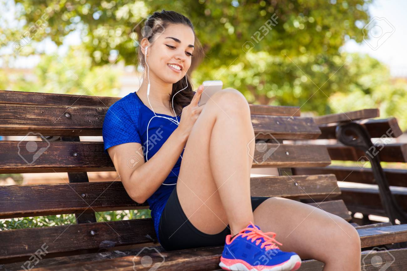 公園でリラックスした女性アスリートを見て 彼女のスマート フォンから音楽を聴いて良い の写真素材 画像素材 Image 公園でリラックスした女性アスリートを見て 彼女のスマート フォンから音楽を聴いて良い の写真素材 画像素材 Image