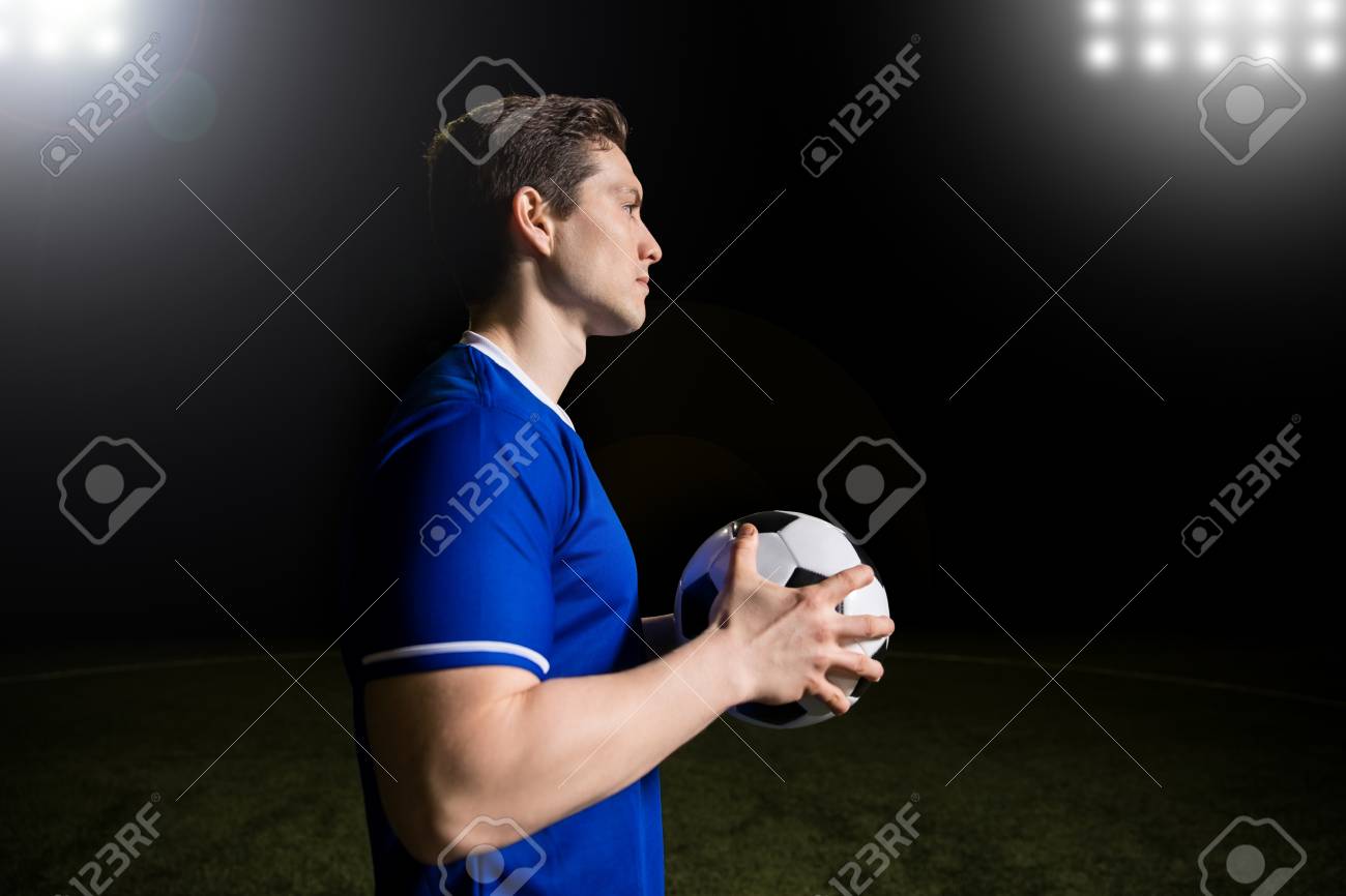 サッカーを手にスポーツフィールドに立つ青いジャージのフィット若いサッカー選手のプロフィール図 の写真素材 画像素材 Image