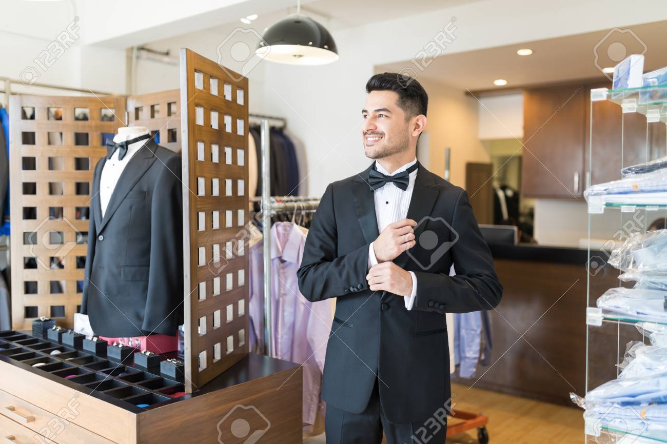 Young customer getting ready for party in suit rental shop
