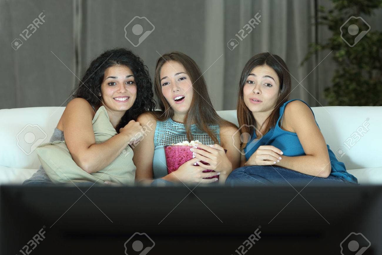 Three friends watching romantic movie on tv sitting on a couch at home - 50564336 Three friends watching romantic movie on tv sitting on a couch at home - 50564336
