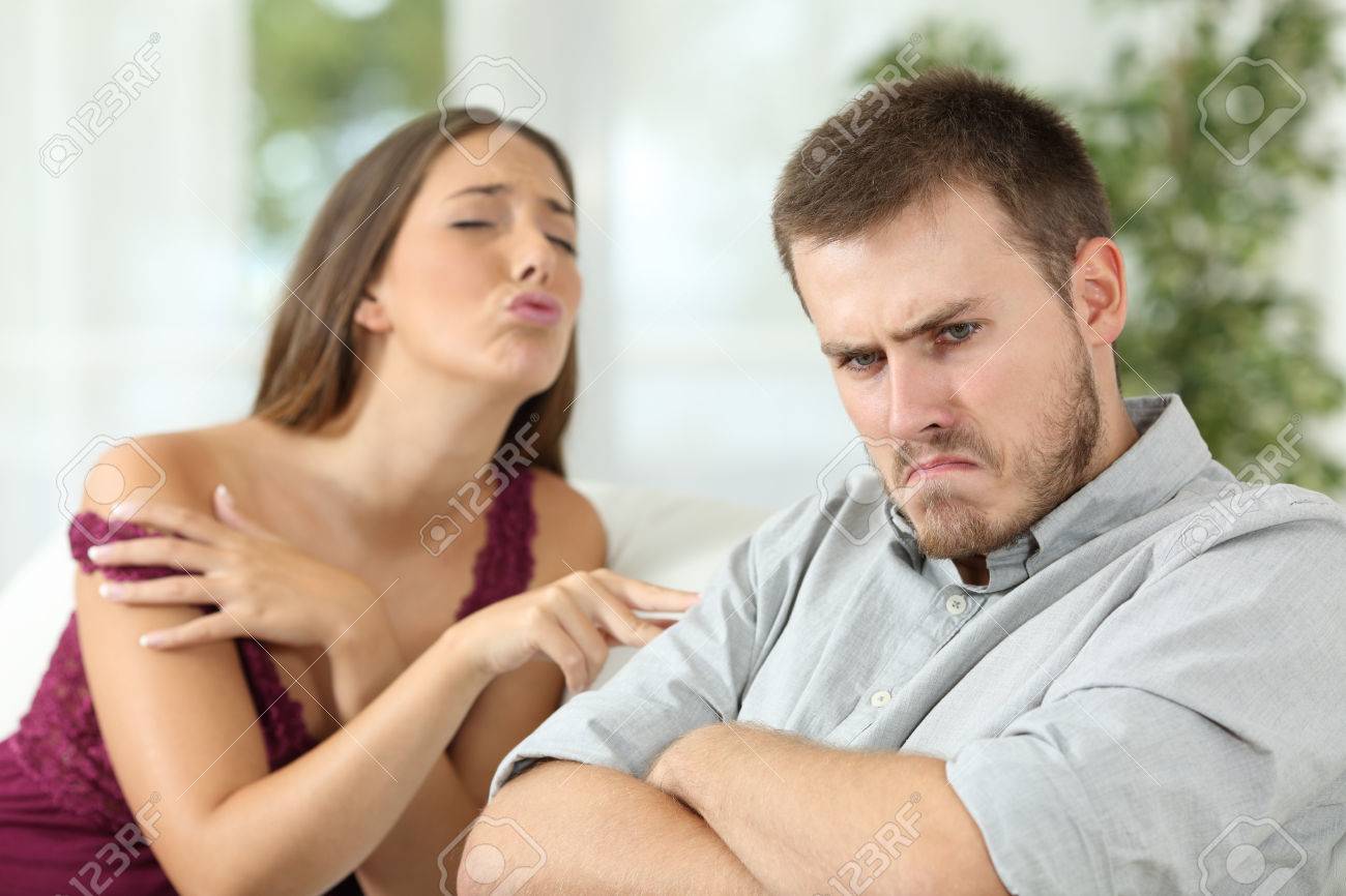 Verärgerter Mann auf einer Couch zu Hause im Wohnzimmer sitzt ein Sex-Angebot von seiner sexy Freundin Ablehnung Verärgerter Mann auf einer Couch zu Hause im Wohnzimmer sitzt ein Sex-Angebot von seiner sexy Freundin Ablehnung
