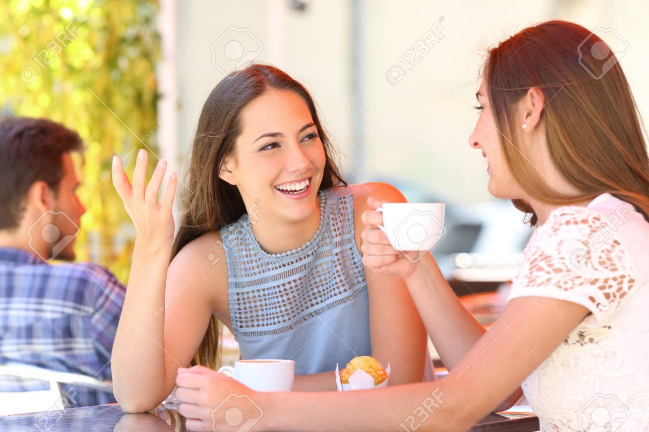 Two happy friends talking and drinking in a coffee shop terrace - 115370481 Two happy friends talking and drinking in a coffee shop terrace - 115370481