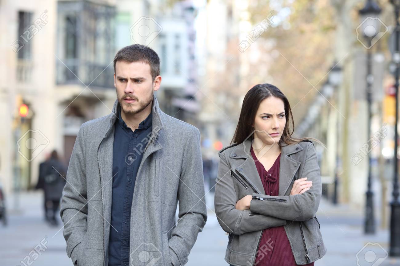Front view portrait of an angry couple walking in the street after argument - 115370815 Front view portrait of an angry couple walking in the street after argument - 115370815