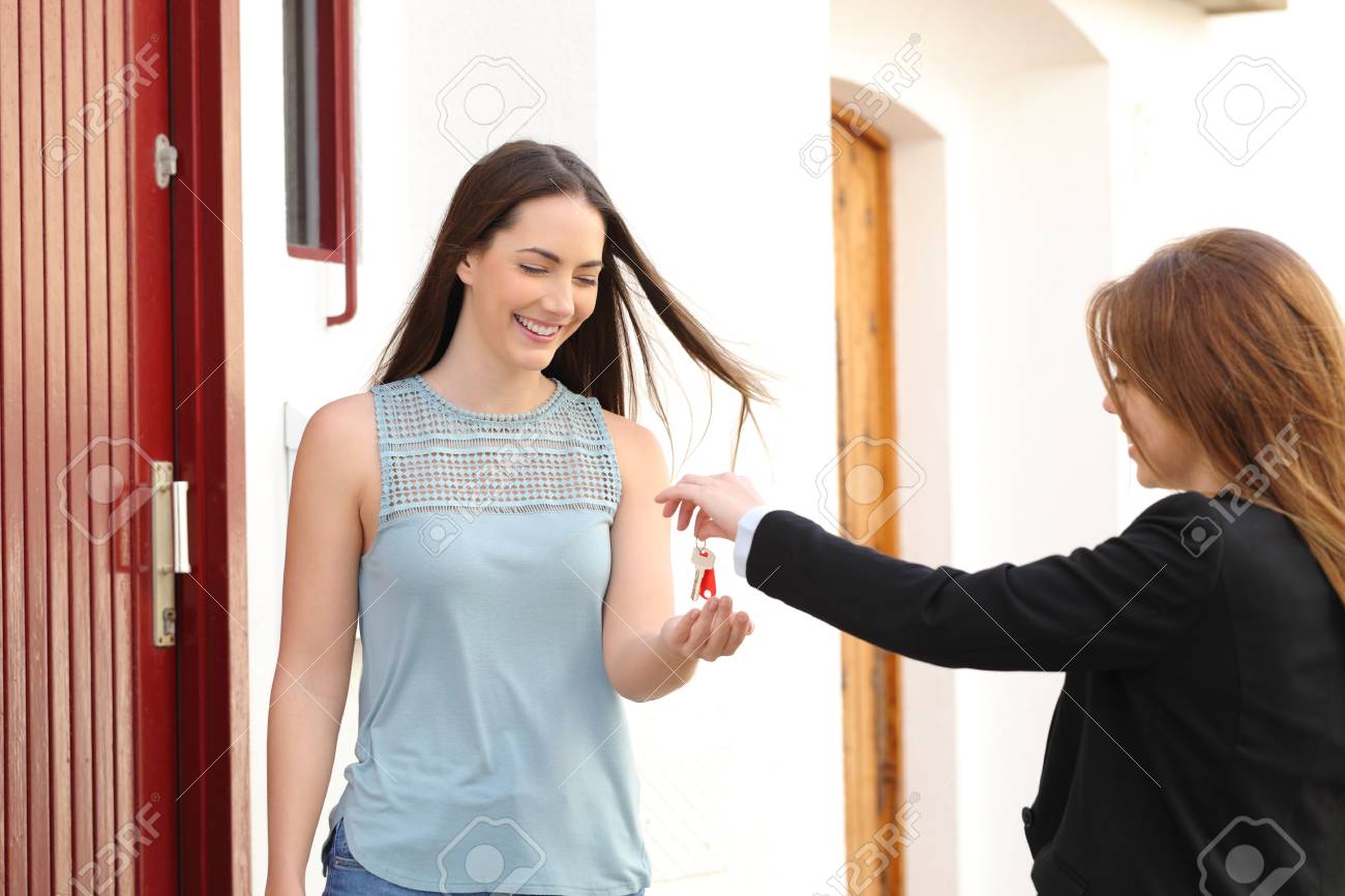 Happy tenant receiving apartment keys from real estate agent in the street - 115371150 Happy tenant receiving apartment keys from real estate agent in the street - 115371150