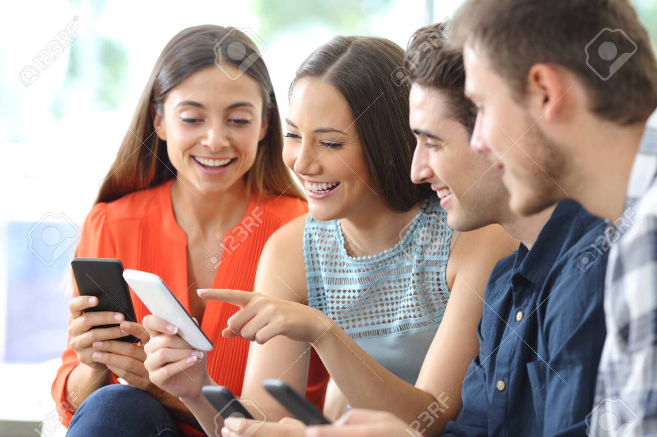 Happy group of friends checking smart phones sitting on a couch in the living room at home - 123603142 Happy group of friends checking smart phones sitting on a couch in the living room at home - 123603142