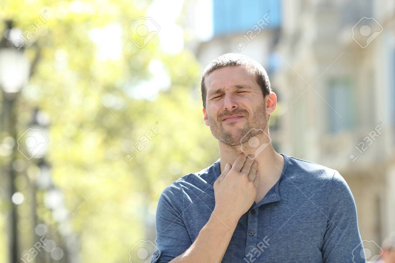 Stressed man suffering throat ache standing alone in the street - 131834868 Stressed man suffering throat ache standing alone in the street - 131834868