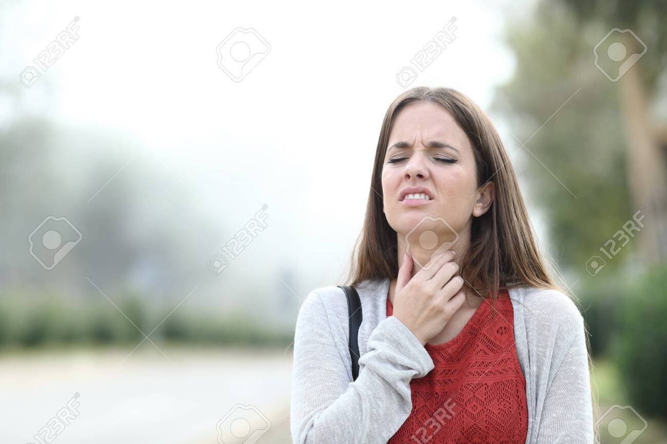 Front view portrait of an ill woman suffering throat sore walks in a park a foggy day - 133951877 Front view portrait of an ill woman suffering throat sore walks in a park a foggy day - 133951877