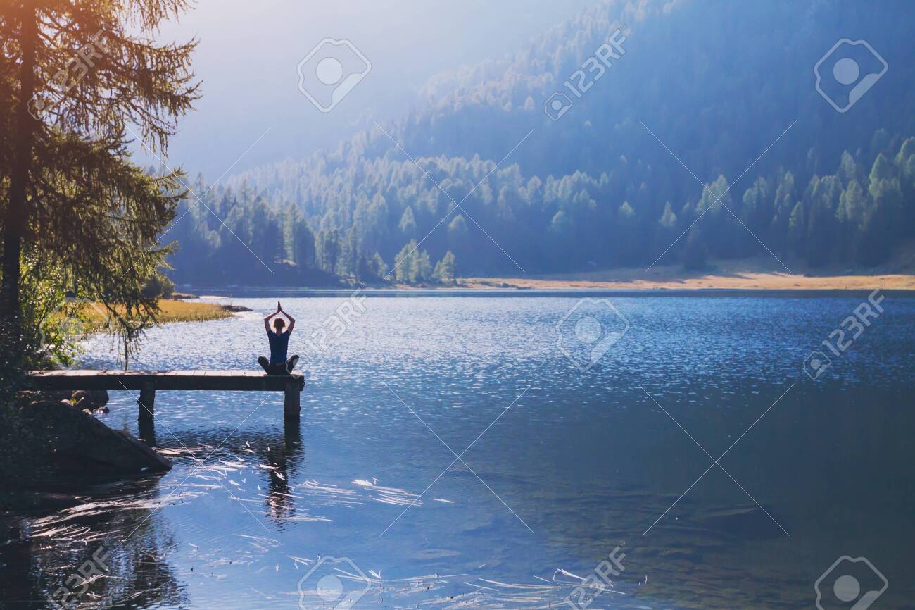 yoga beautiful background, harmony in life, meditation practice, silhouette of woman sitting in lotus position on the pier of lake and doing breathing exercises in beautiful landscape - 145035207 yoga beautiful background, harmony in life, meditation practice, silhouette of woman sitting in lotus position on the pier of lake and doing breathing exercises in beautiful landscape - 145035207