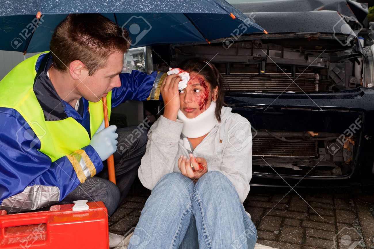 Paramedic caring for an injured woman under an umbrella - 10619945 Paramedic caring for an injured woman under an umbrella - 10619945