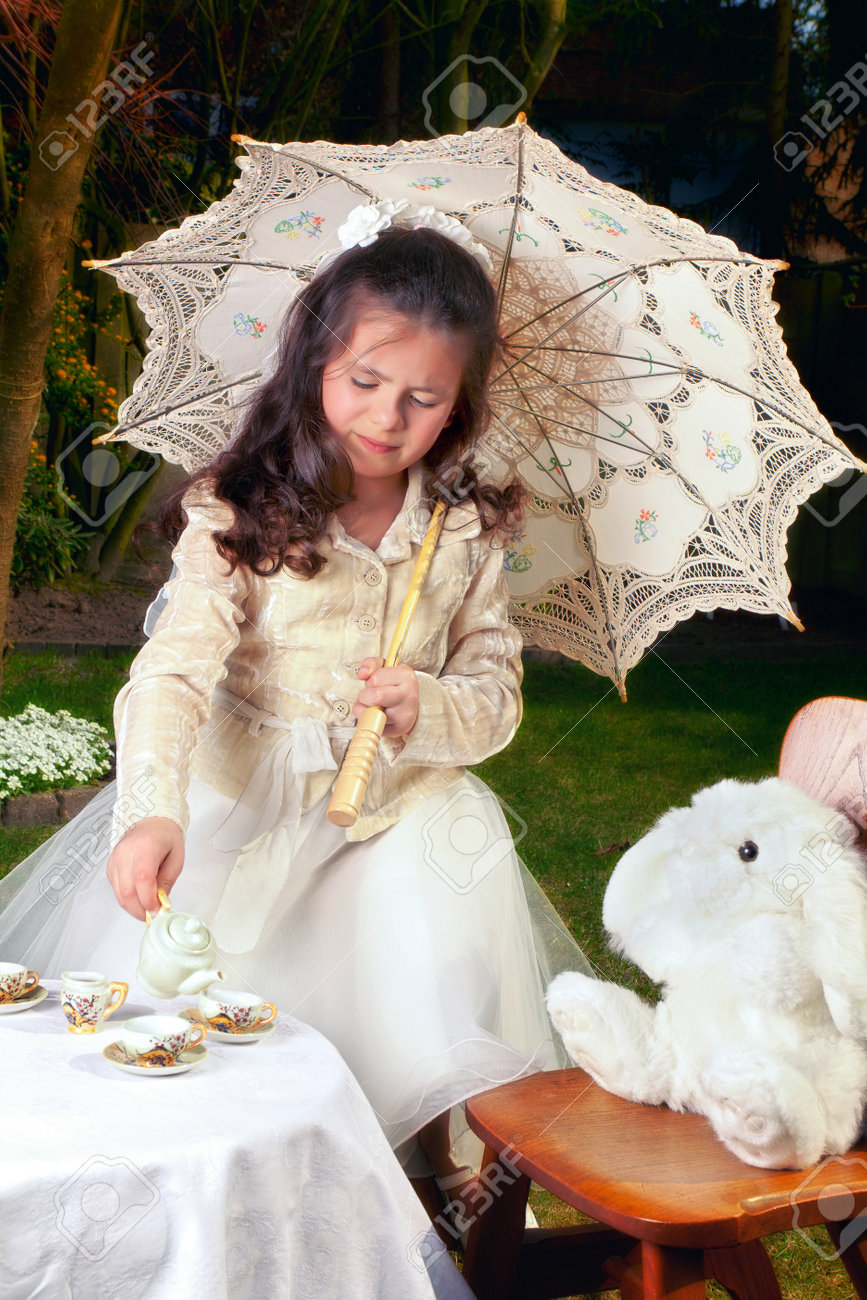 女の子に扮したアリス不思議の国の少女の白ウサギとお茶を飲む の写真素材 画像素材 Image
