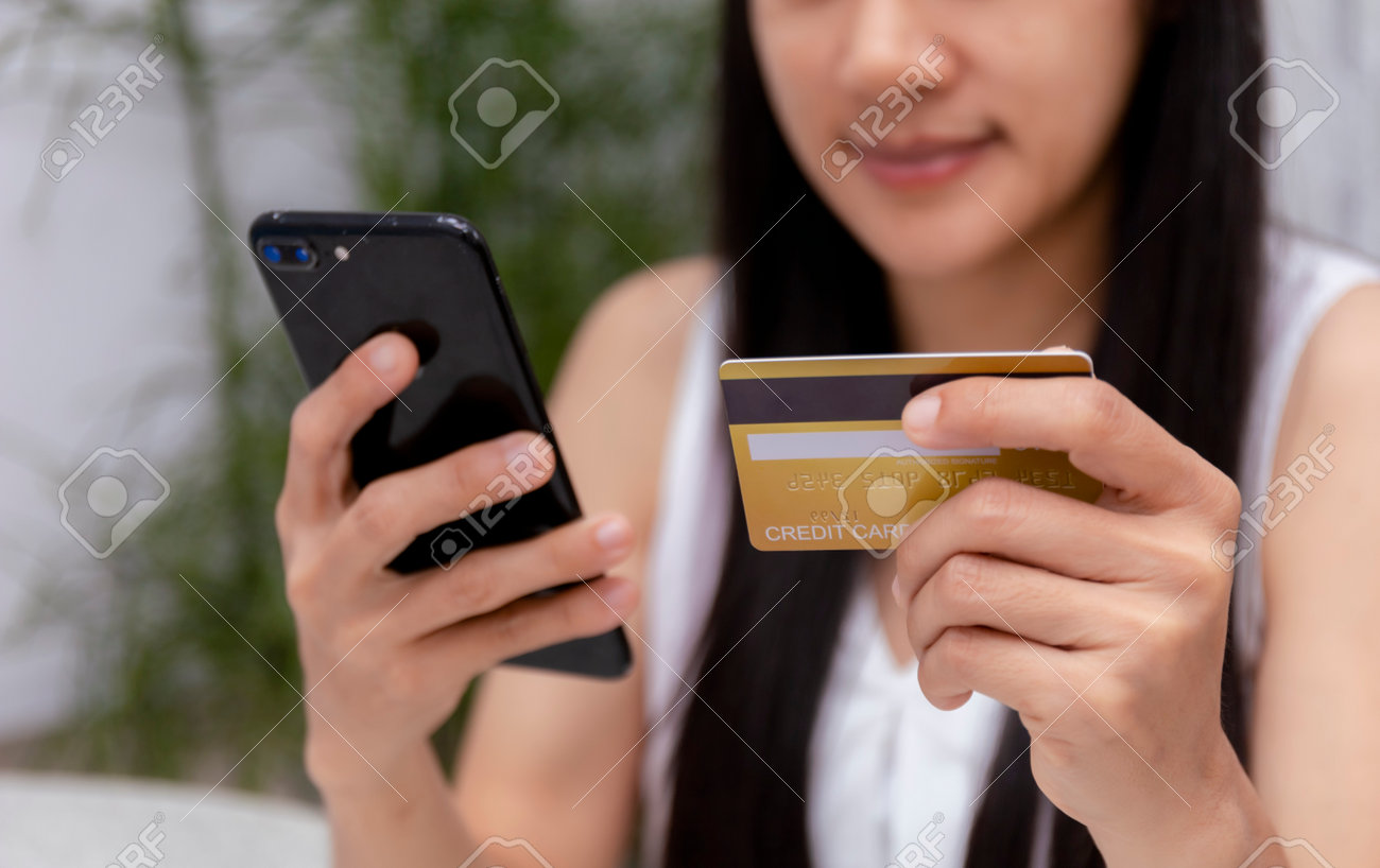 Young woman holding credit card and using laptop computer. Women working at home. Online shopping, e-commerce, internet banking, spending money, working from home concept. Technology shopping online concept. - 167372121 Young woman holding credit card and using laptop computer. Women working at home. Online shopping, e-commerce, internet banking, spending money, working from home concept. Technology shopping online concept. - 167372121