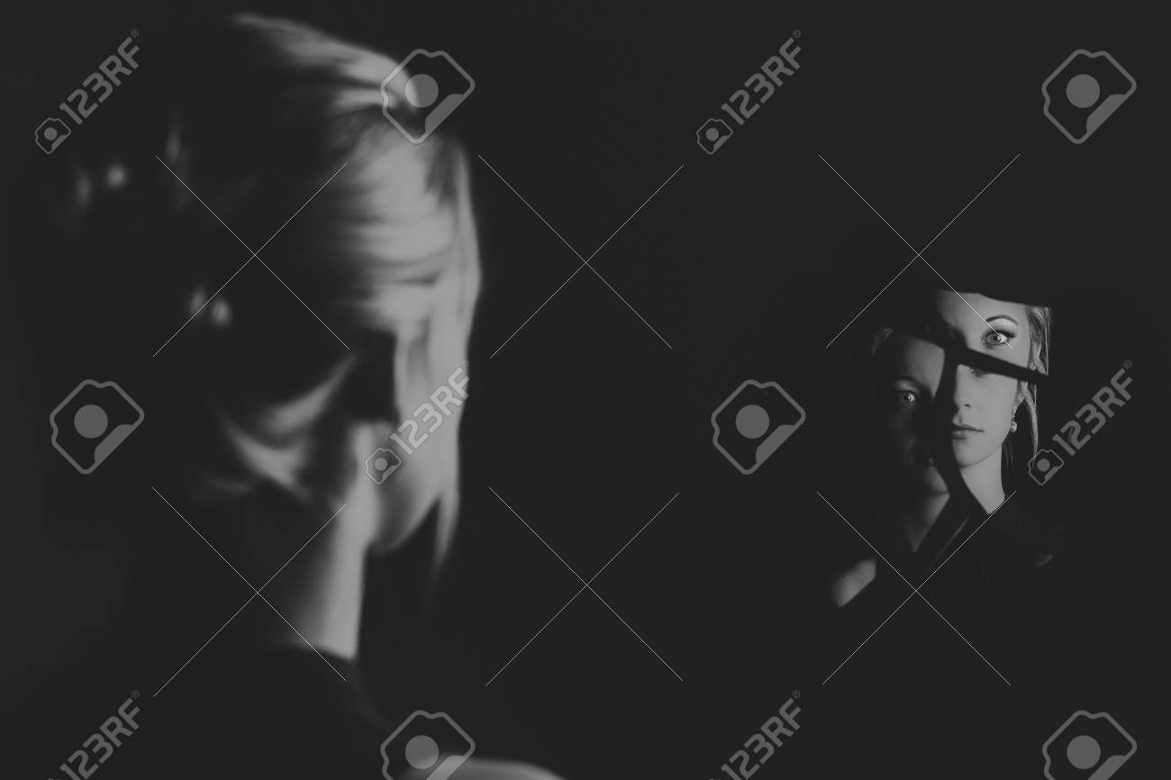 woman looking at her face in shards of broken mirror pieces artistic