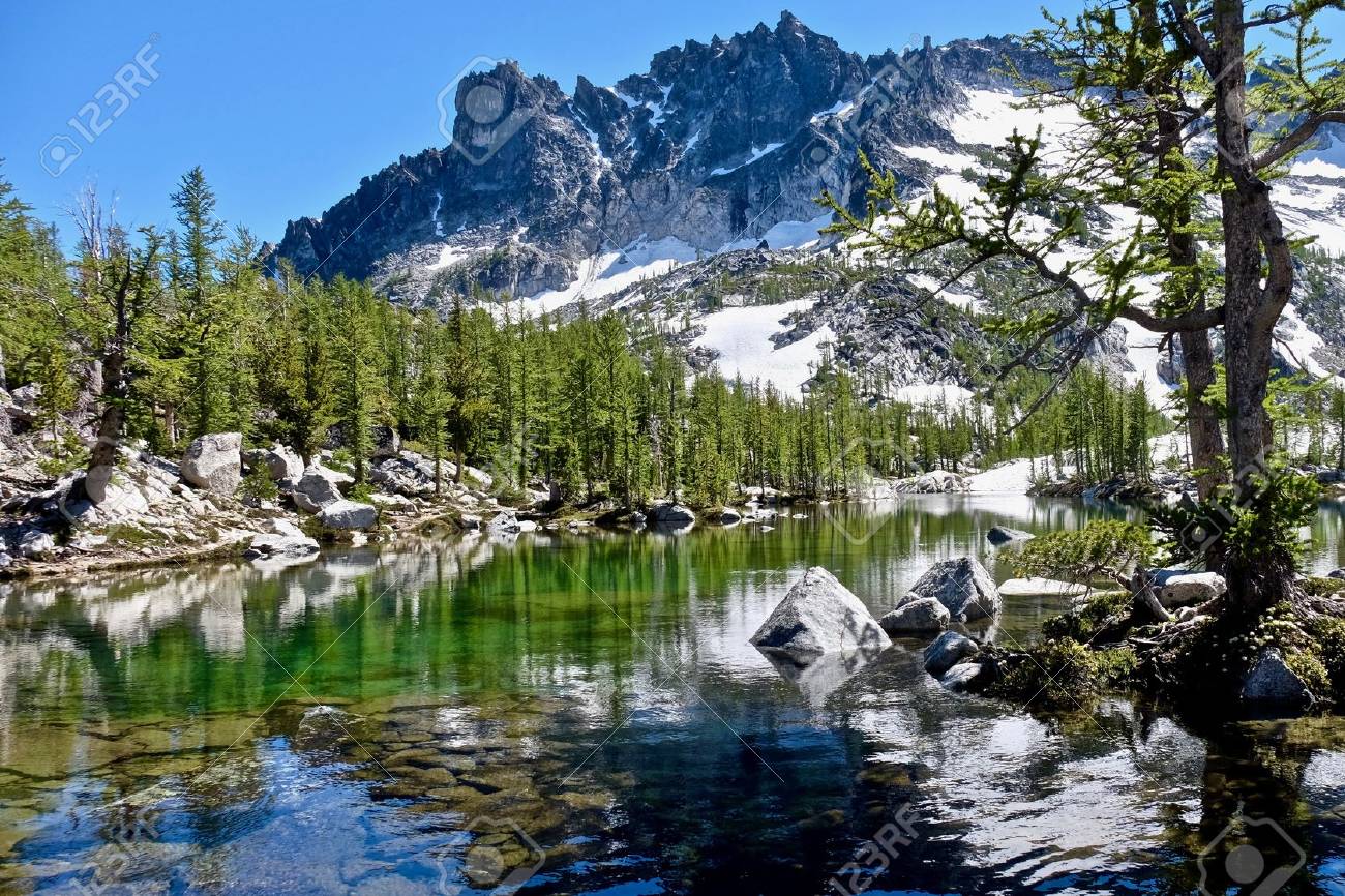 sunlit alpine forest crystal clear lake and granite mountain