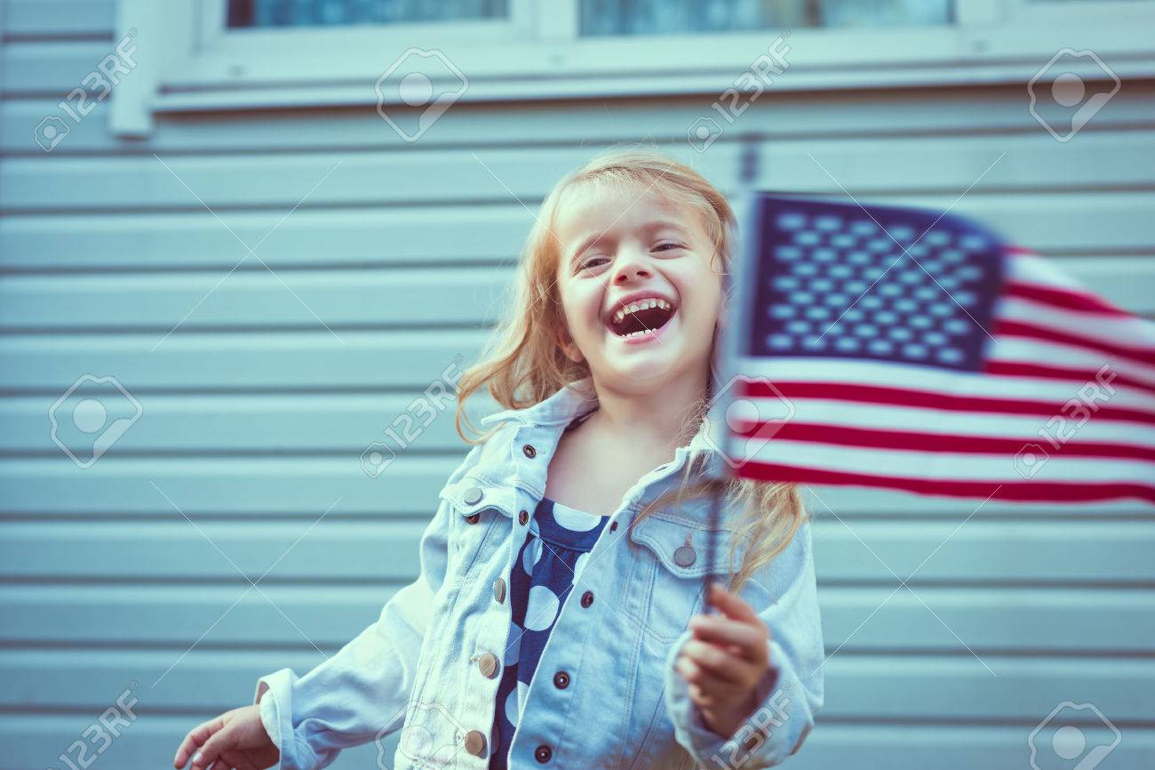 笑いとアメリカの国旗を振って長い巻き毛のブロンドの髪のかわいい女の子 独立記念日 国旗の日コンセプト ヴィンテージやレトロな色 の写真素材 画像素材 Image