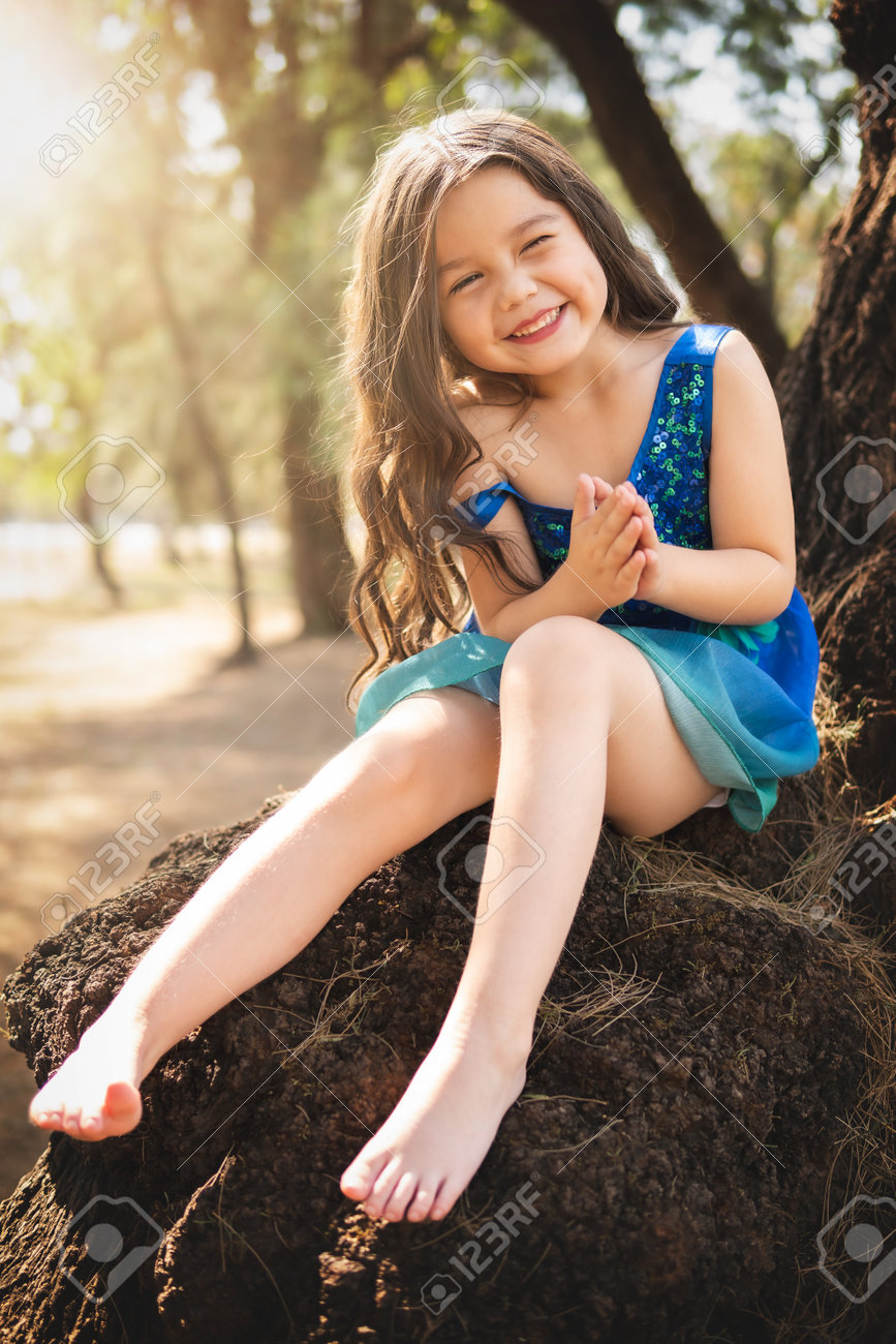 Beautiful Happy Girl Playing In The Park With Blue Dress Without Shoes  Sitting On Tree Laughing Screaming With Happiness In Family Enjoying  Children's Day Stock Photo, Picture and Royalty Free Image. Image, image size:867x1300