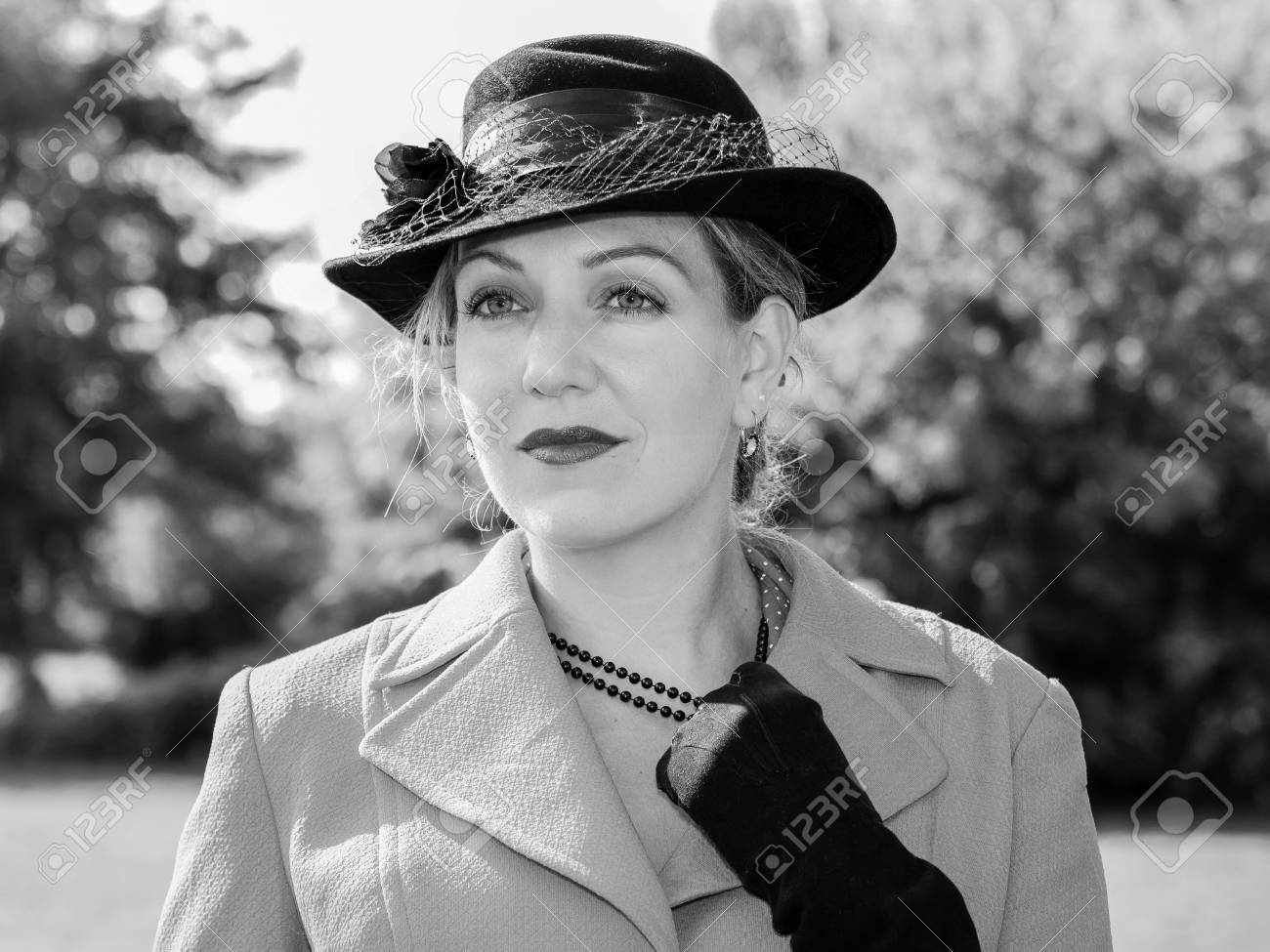 Stock photo vintage black and white portrait of a woman with a suit and a black hat looking dreamily