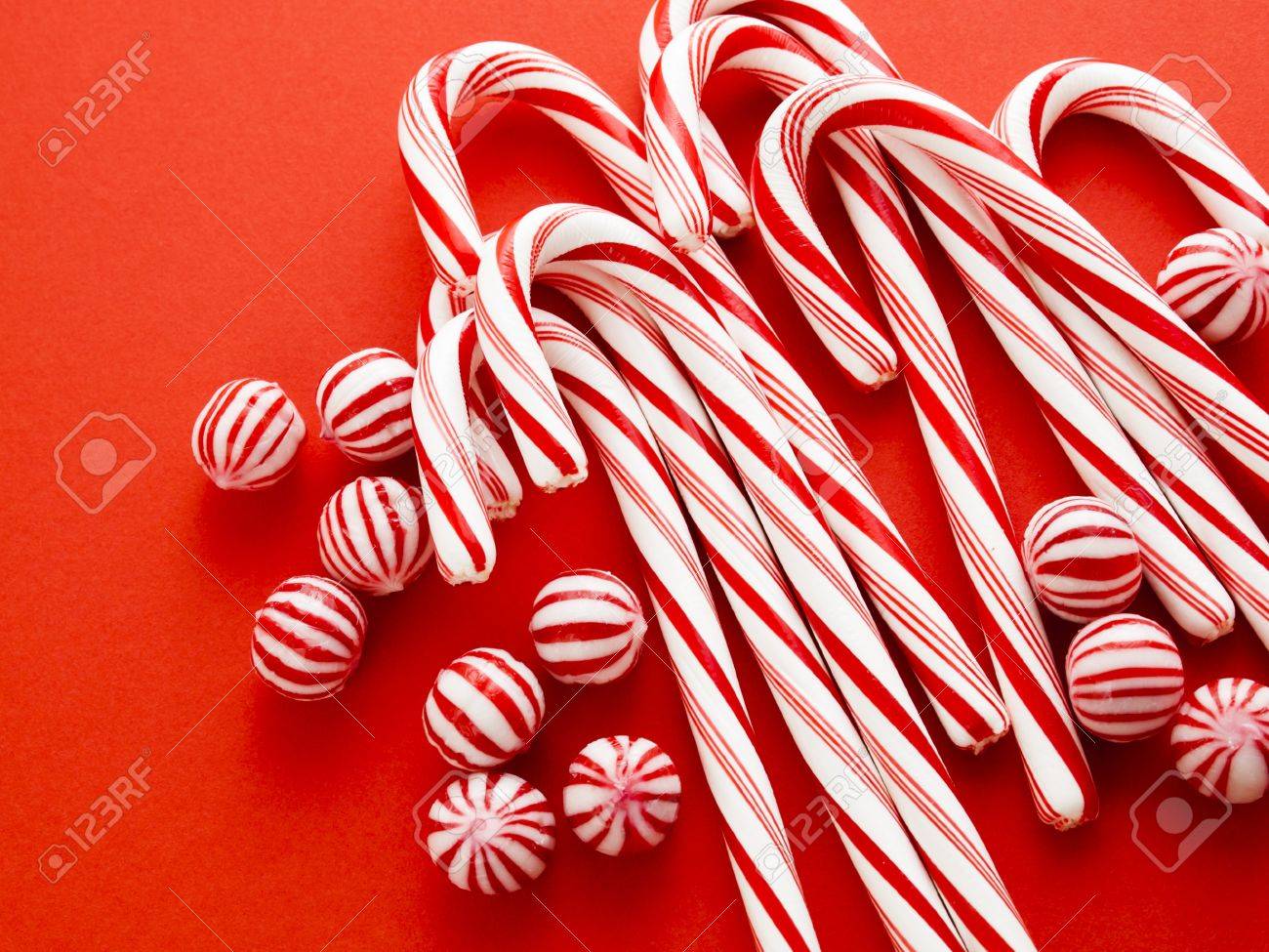 white and red peppermint candy canes on red background stock photo