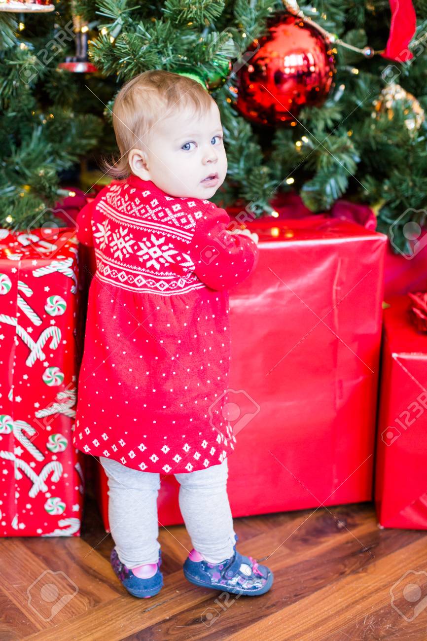 クリスマス ツリーの横にあるスカンジナビアの赤いドレスの女のかわいい赤ちゃん の写真素材 画像素材 Image