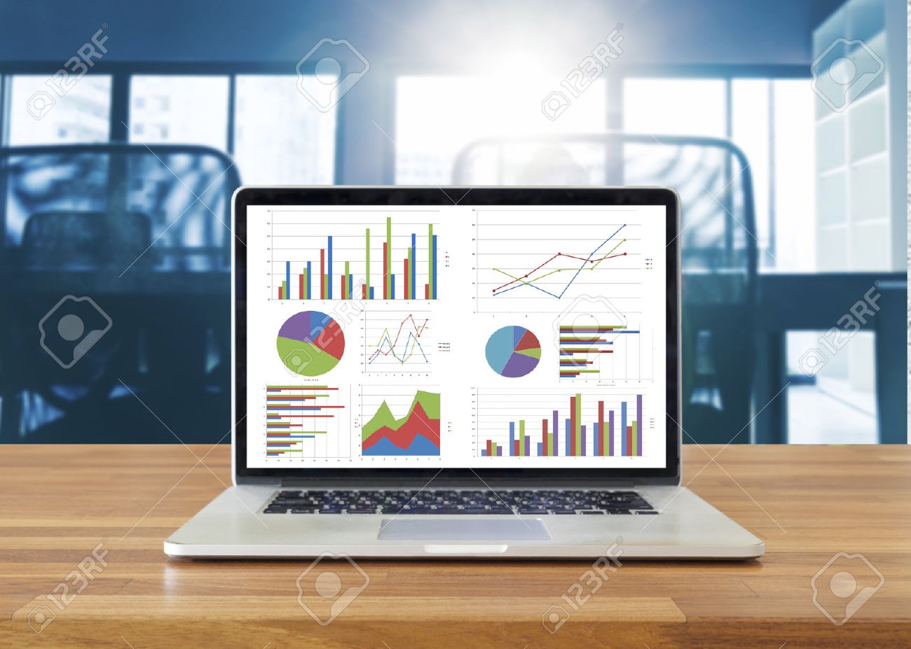 laptop on wooden table showing charts and graph against office laptop charts