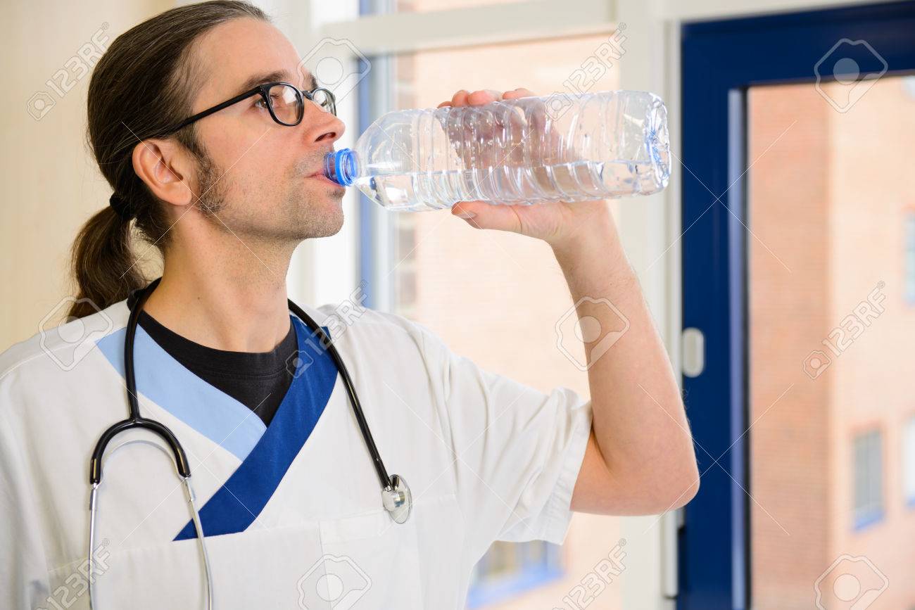 長い髪の男性看護師は のどが渇いて飲むと水 の写真素材 画像素材 Image