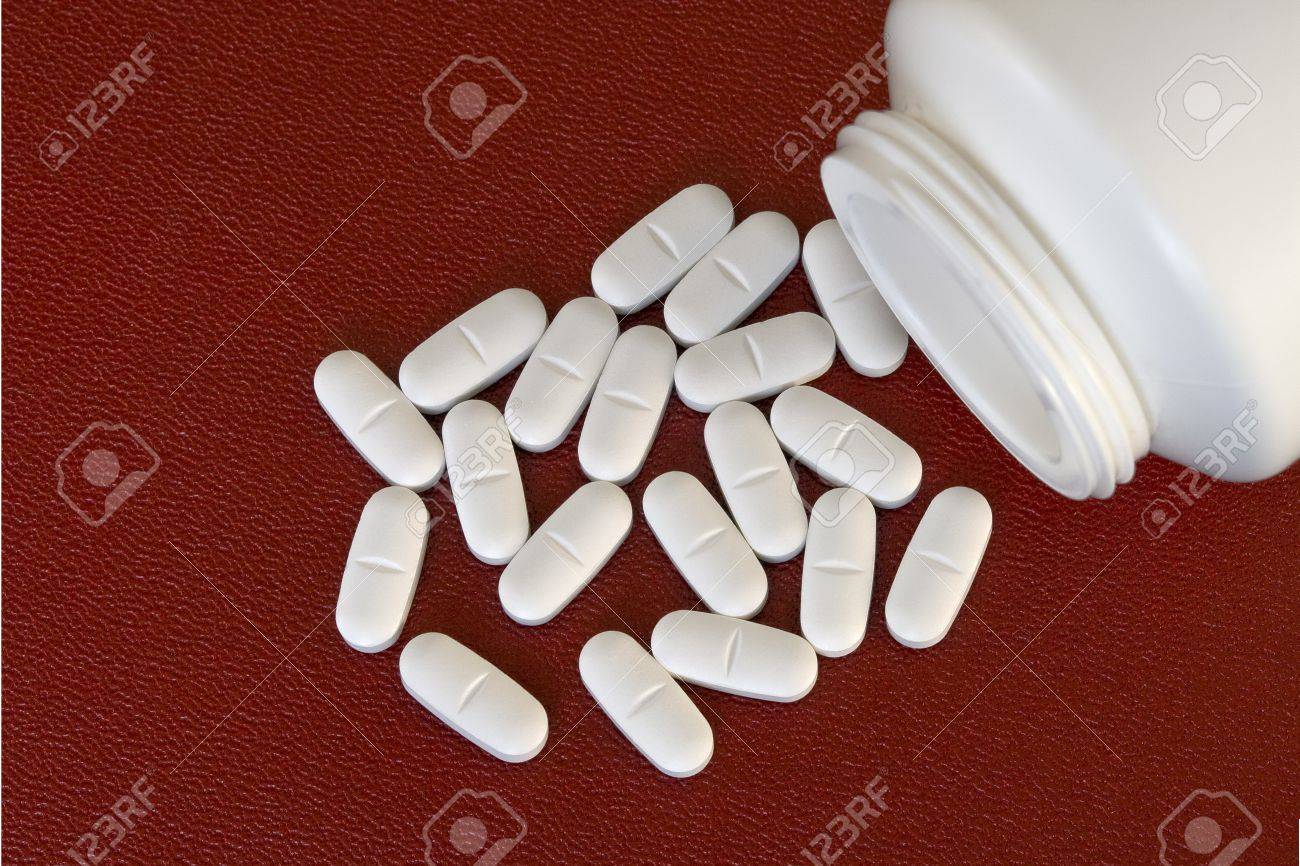 白 楕円形の錠剤 赤い背景の上の薬瓶 の写真素材 画像素材 Image