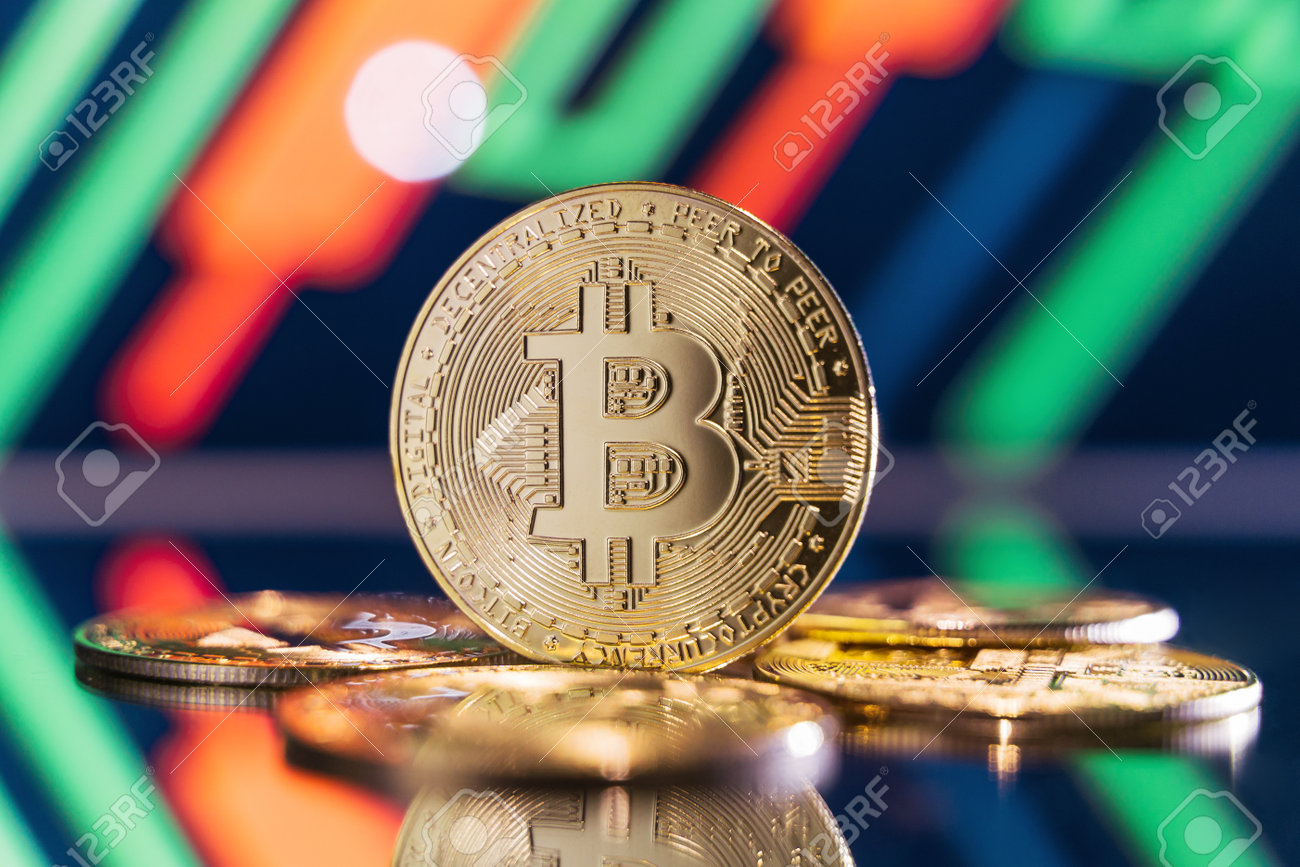 ぼやけた背景に鏡面に立つ金色のビットコインと、緑と赤のローソク足を持つ暗号チャート。暗号通貨取引市場のコンセプトの写真素材・画像素材 Image  201133397