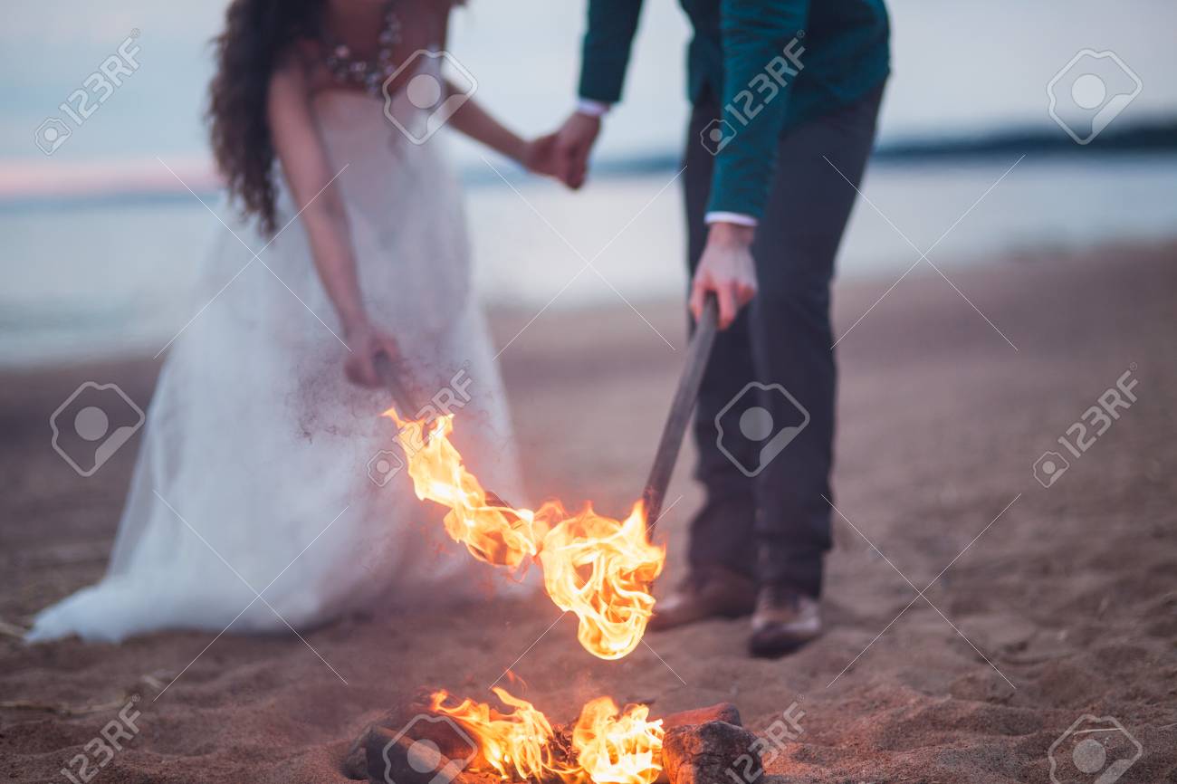 カップル ライト日没に水の近くのビーチの松明 の写真素材 画像素材 Image